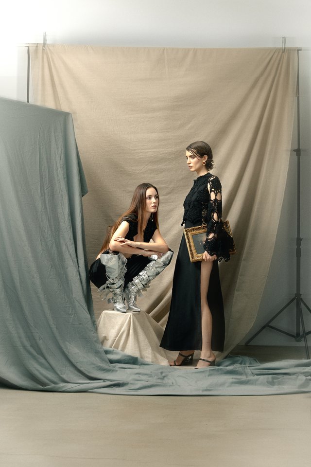 Dos modelos con prendas negras y pantalón metalizado